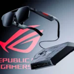 Close-up product shot of the ROG XREAL R1 gaming glasses on a table, showcasing its sleek design as a high-refresh-rate wearable display for PC and console gaming.
